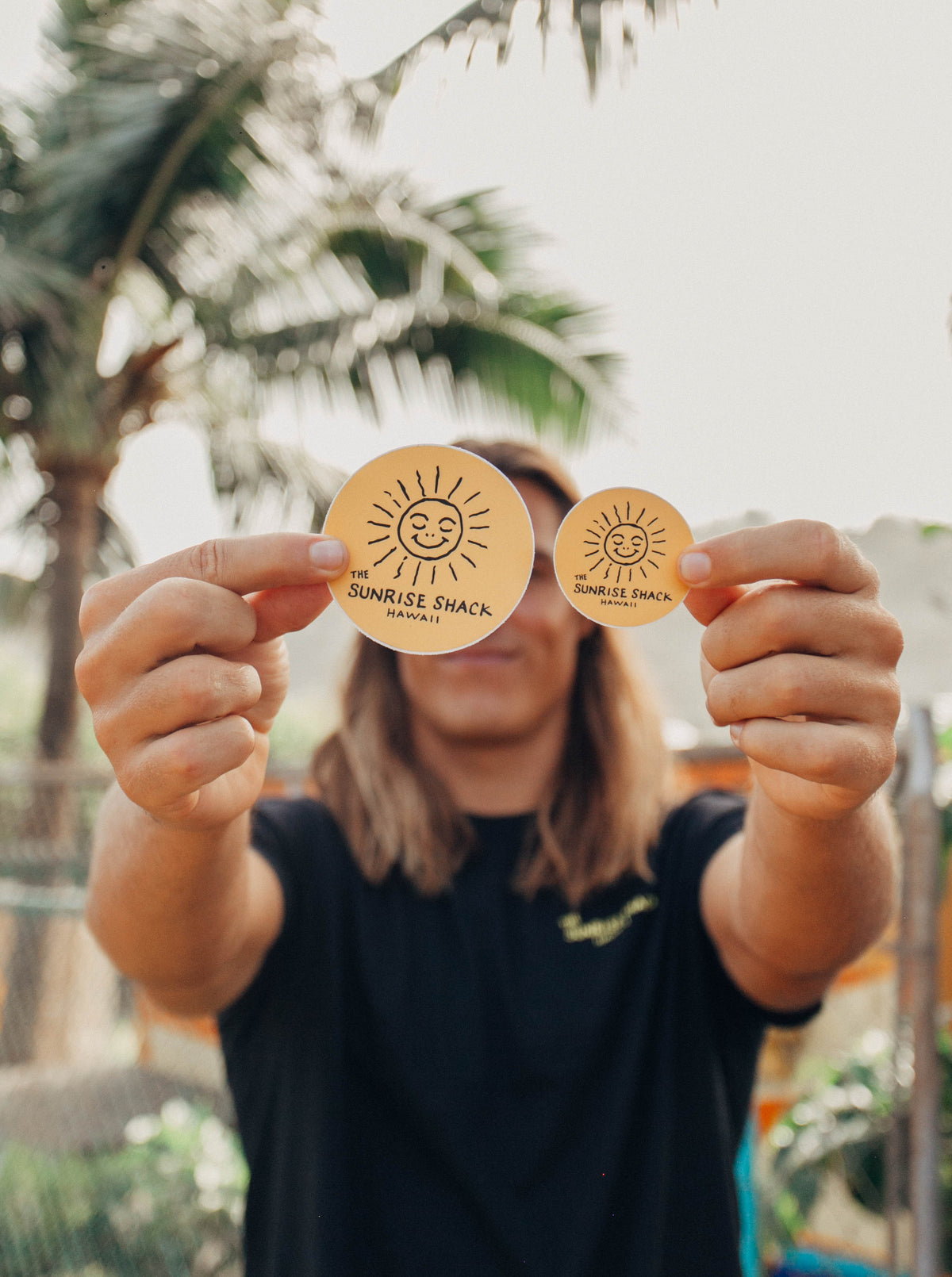 Two circle stickers, one large and small, of smiling sunshine. Black on yellow background.